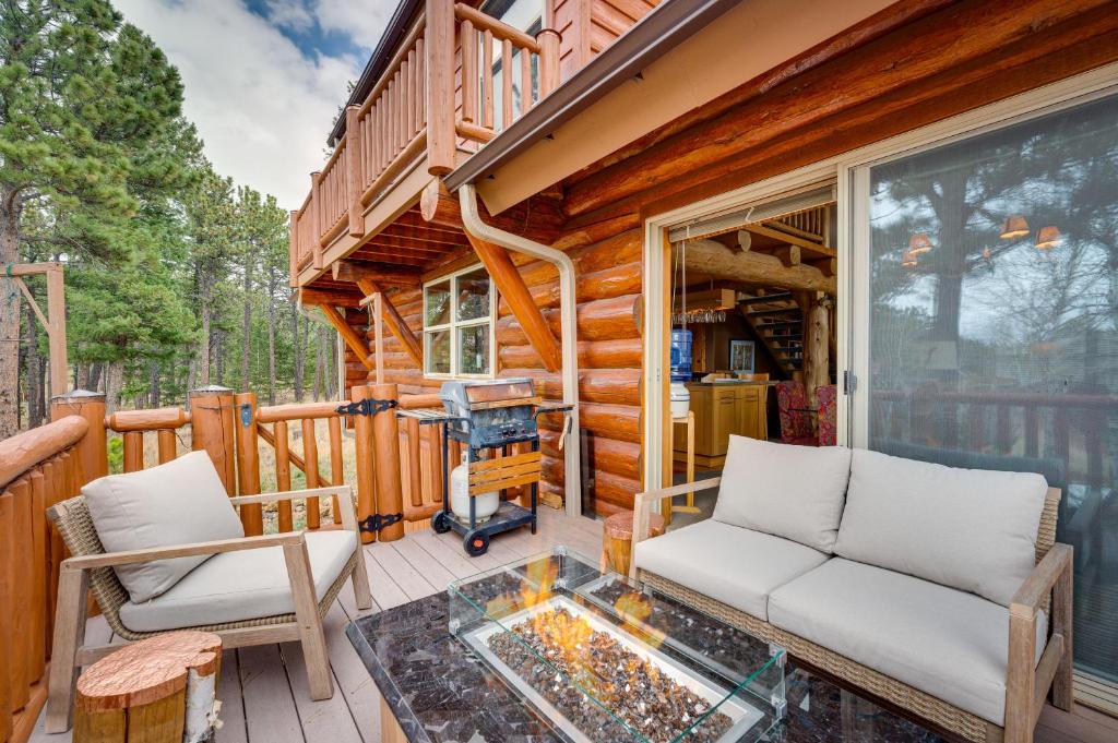 a log cabin porch with two chairs and a couch at Rustic Ward Retreat with Deck and Mountain Views! in Ward