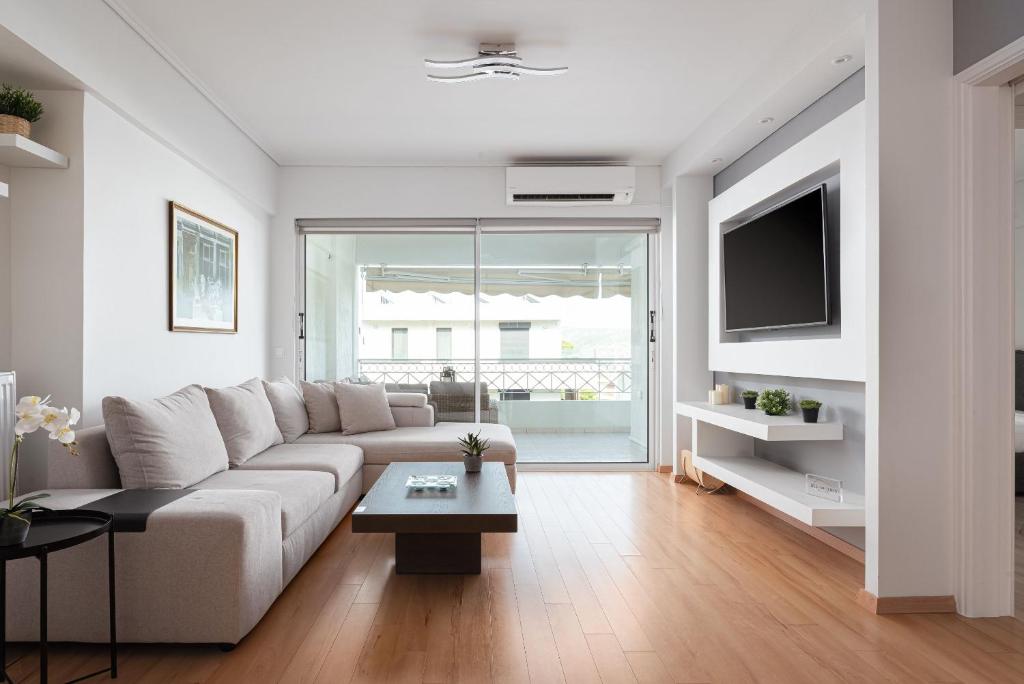 a white living room with a couch and a tv at Athenian Riviera Executive Apartment in Vari