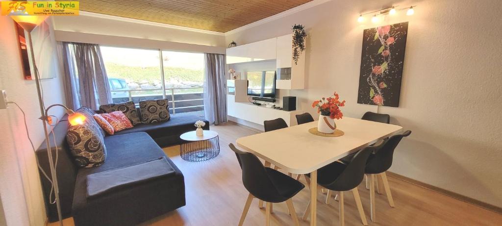 - un salon avec un canapé et une table avec des chaises dans l'établissement Apartment Almkogel by FiS - Fun in Styria, à Tauplitz