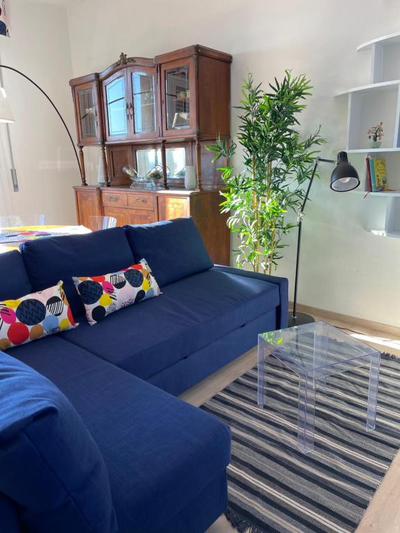 een blauwe bank in een woonkamer met een glazen tafel bij Bilocale di charme in centro in Parma
