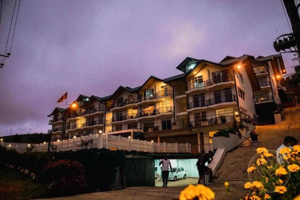 a hotel with people standing outside of it at night at Kapri Luxury Apartment in Nuwara Eliya