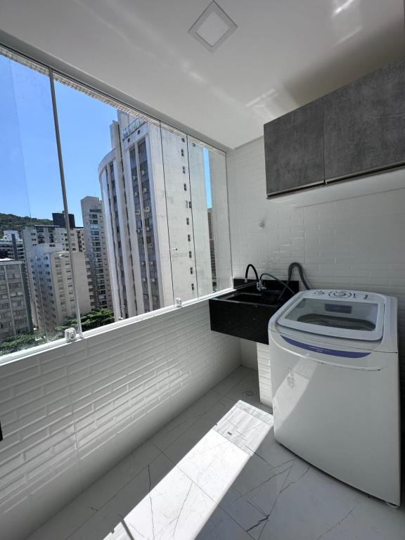 a white kitchen with a view of a city at Frente ao mar Pitangueiras - 3 suítes in Guarujá