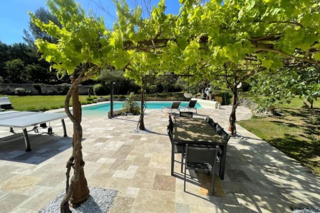 une terrasse avec une table, des arbres et une piscine dans l'établissement Magnifique villa familiale tout confort à 10 min d'Aix-en-Provence, à Ventabren