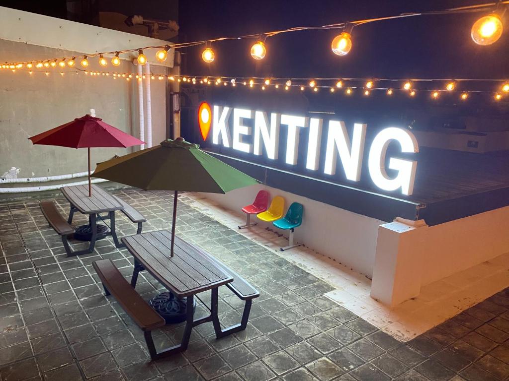 deux tables avec des parasols et des chaises devant un panneau dans l'établissement Kenting Southern Dream Resort, à Kenting