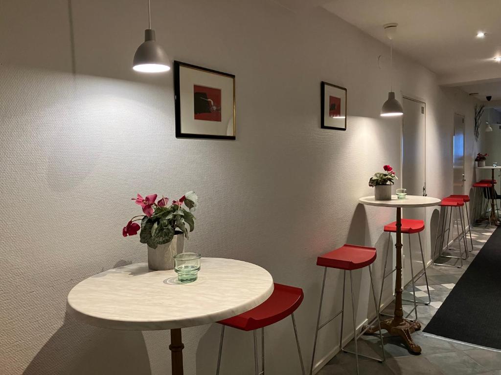 a room with two tables and red stools at Bella Hostel in Turku