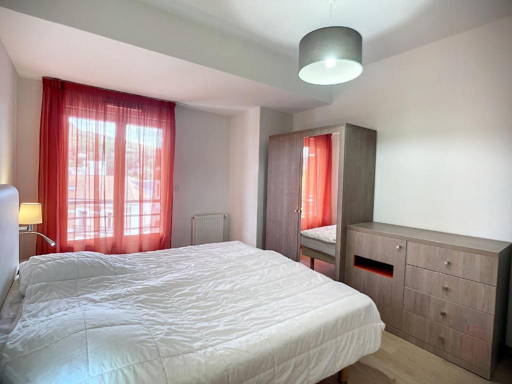 une chambre avec un lit et une fenêtre avec des rideaux rouges dans l'établissement Bel F2 climatisé, terrasse, parking, à 50m des Thermes de Lamalou-les-Bains, animaux acceptés - FR-1-451-193, à Lamalou-les-Bains