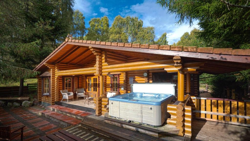 a log cabin with a hot tub on a deck at Beaver Creek Lodge in Aviemore
