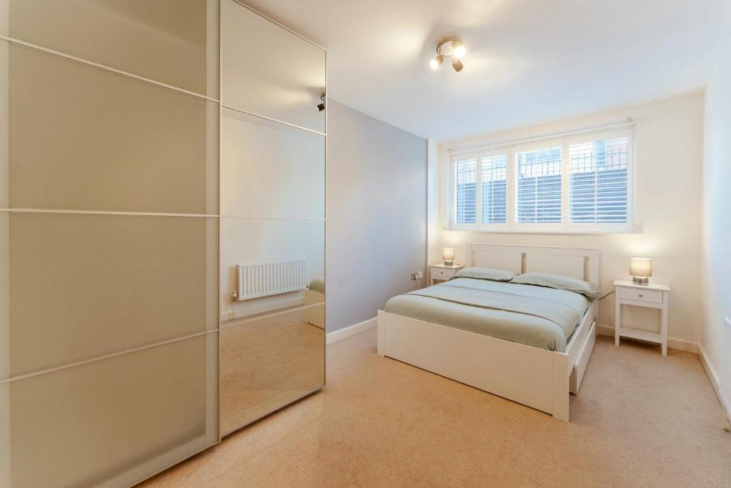 een slaapkamer met een bed en een grote glazen kast bij Brick Lane & Shoreditch London Apartment in Londen