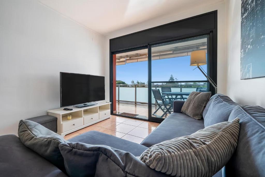 sala de estar con sofá y TV de pantalla plana en Appartement de vacances avec vue mer , terrasses , solarium et Wi-Fi, en L'Eucaliptus