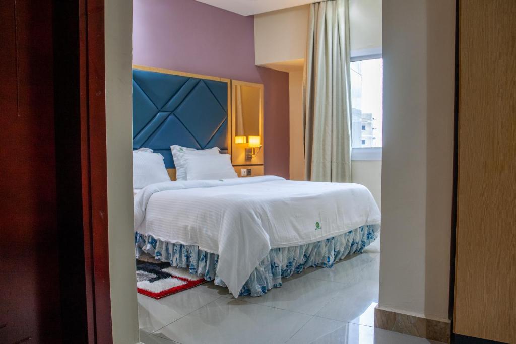 Un dormitorio con una gran cama blanca y una ventana en HOTEL MICKEL en Duala
