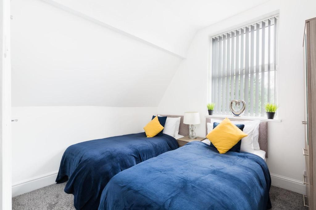two beds in a room with blue and yellow pillows at Sapphire Suite Moseley Mews by StayStaycations in Birmingham