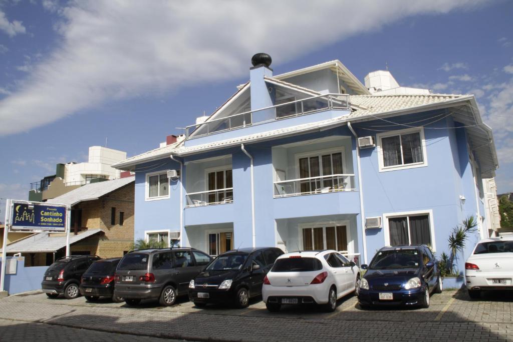 un edificio blanco con coches estacionados en un estacionamiento en Pousada Cantinho Sonhado, en Bombinhas