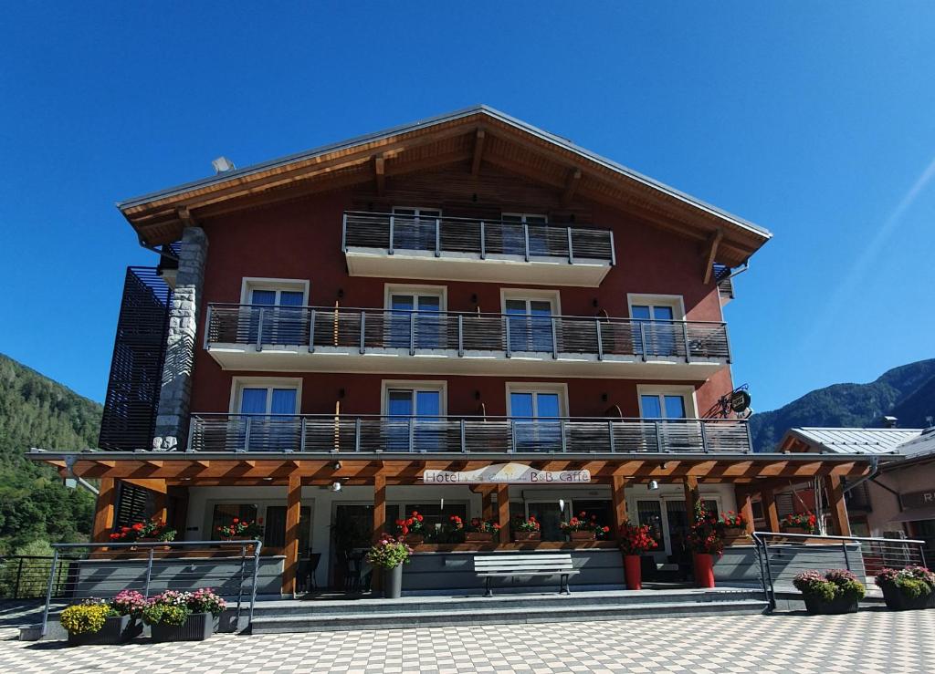 um grande edifício vermelho com uma varanda em Hotel Gran Vacanze Rooms & Apartments em Dimaro