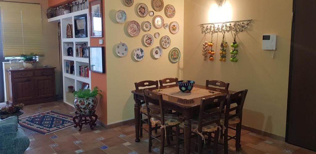 uma sala de jantar com uma mesa e cadeiras e pratos na parede em LA CASA DI ENZA em Santa Margherita di Belice