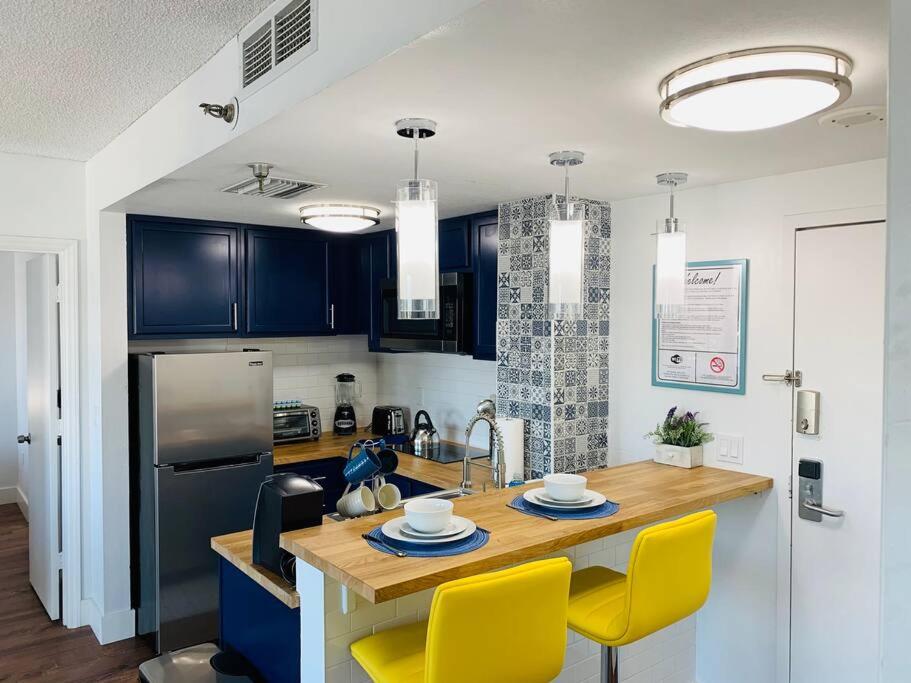 a kitchen with blue cabinets and a table with yellow chairs at Universal Studios. Amazing 2 bedroom apartment! in Orlando