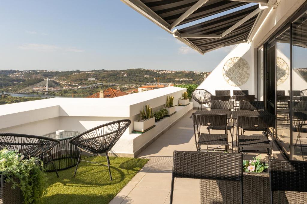 eine Terrasse mit Stühlen und Tischen auf dem Dach in der Unterkunft Penedo da Saudade Suites & Hostel in Coimbra