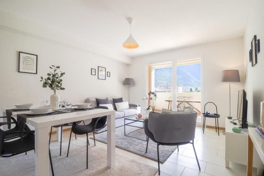 una sala de estar blanca con mesa y sillas en Modern apartment close to Martigny train station en Martigny-Ville