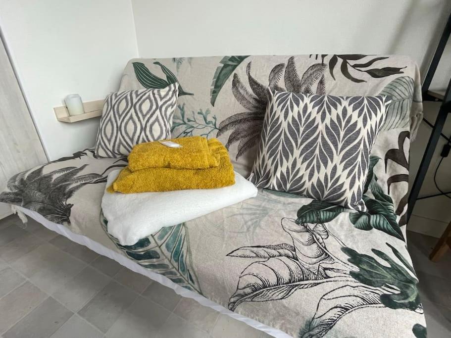 a bed with a yellow blanket and pillows on it at St Bruno - Studio « Palmiers » in Grenoble