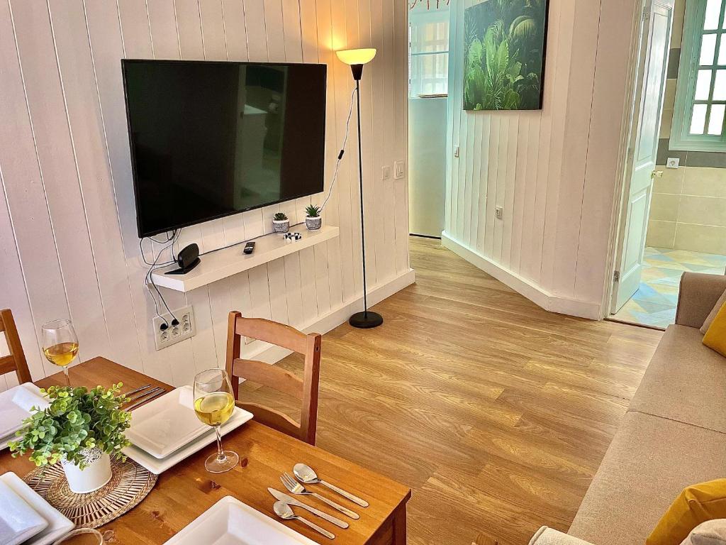 a living room with a table and a television on a wall at Las Brisas 1 by SunHousescanarias in Las Palmas de Gran Canaria