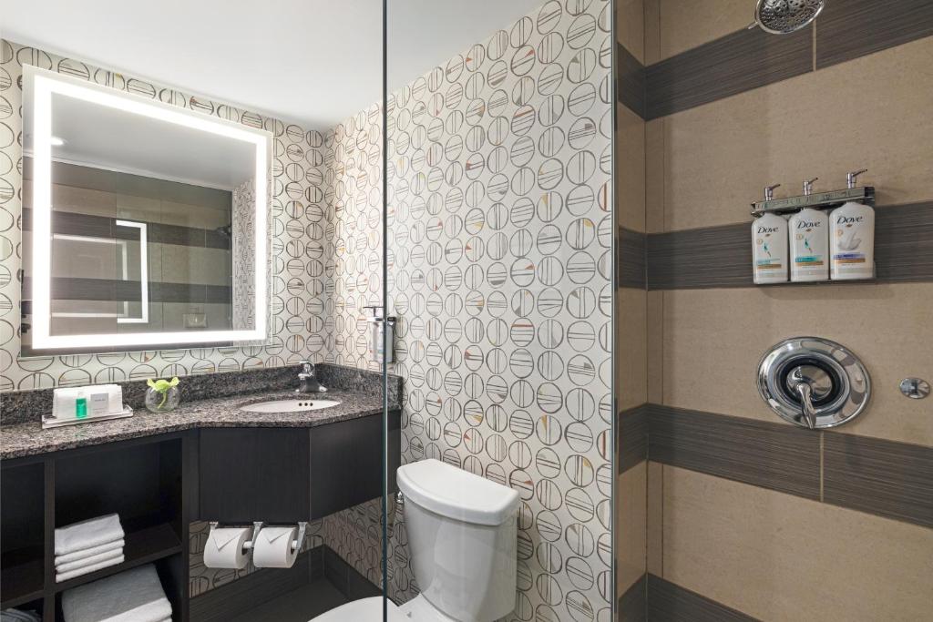 a bathroom with a toilet and a sink and a mirror at Holiday Inn Toronto Downtown Centre by IHG in Toronto