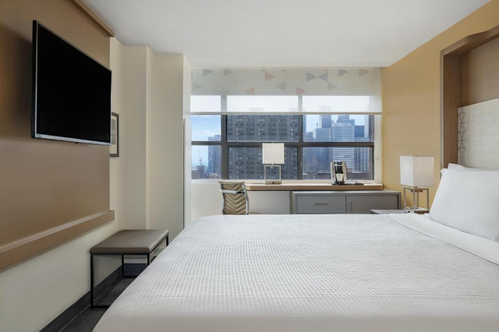 a hotel room with a bed and a desk with a window at Holiday Inn Toronto Downtown Centre by IHG in Toronto