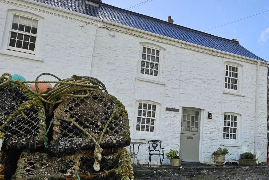 a white brick building with a statue in front of it at Beach Hill Cottage in Portloe
