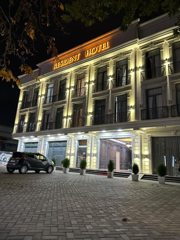um edifício com um carro estacionado em frente em Resident Hotel em Tashkent