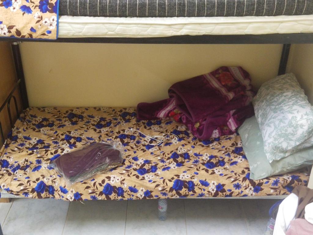 een onderste stapelbed met kleding en kussens erop bij Bed space abu shagara park in Sharjah