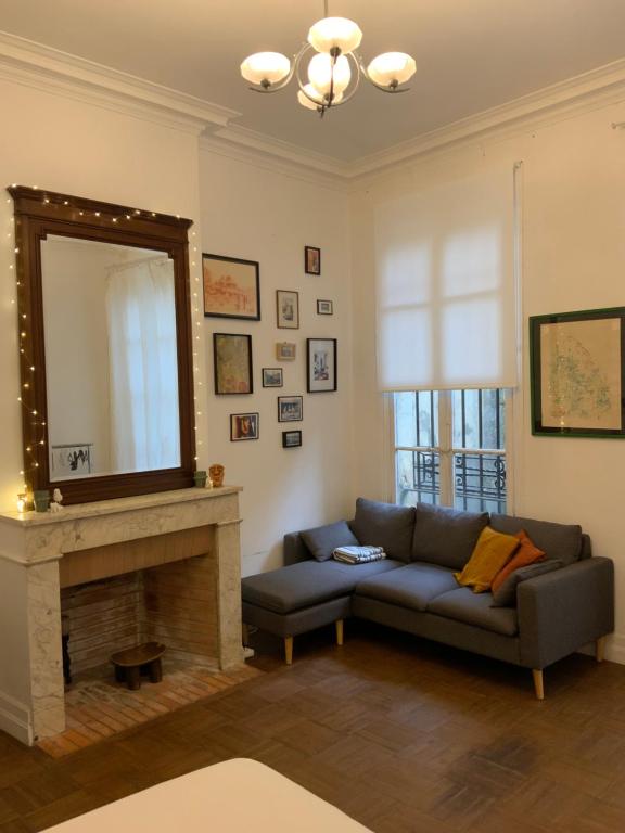 a living room with a couch and a mirror at Grand studio style bordelais dans le triangle d'or in Bordeaux