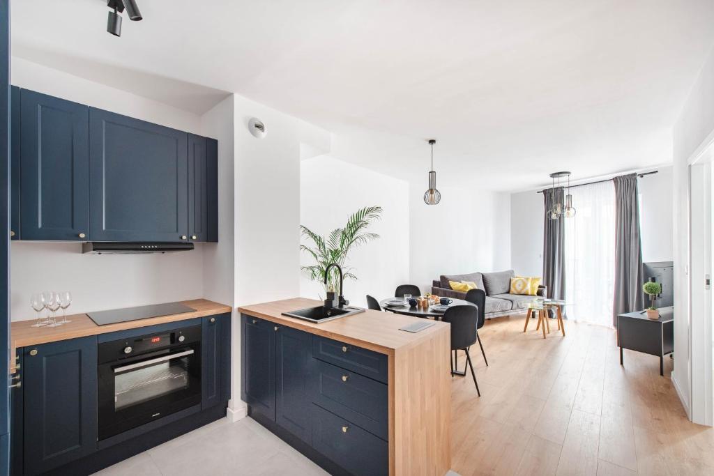 a kitchen with blue cabinets and a living room at Spacious and modern Apartment Lwowska, close to Kazimierz in Kraków