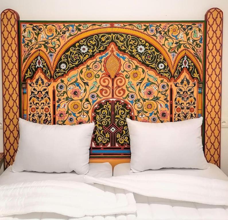 ein Bett mit einem bunten Kopfteil mit zwei Kissen in der Unterkunft Dar Al Mardi Fes in Fès