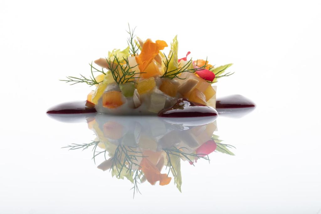 a plate of fruit on a table with its reflection at Palazzo Tirso MGallery Cagliari in Cagliari