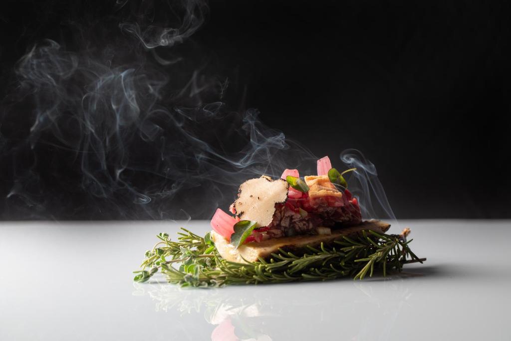 a piece of food with smoke on a table at Palazzo Tirso MGallery Cagliari in Cagliari