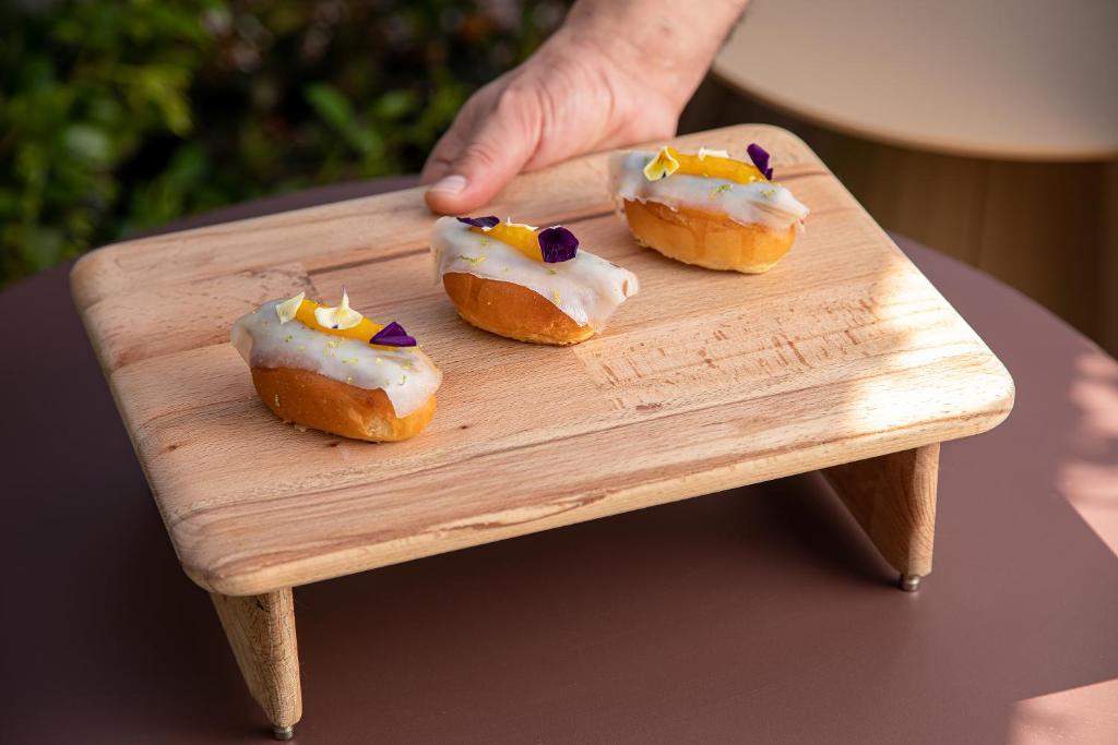 three donuts with white icing on a wooden board at Palazzo Tirso MGallery Cagliari in Cagliari