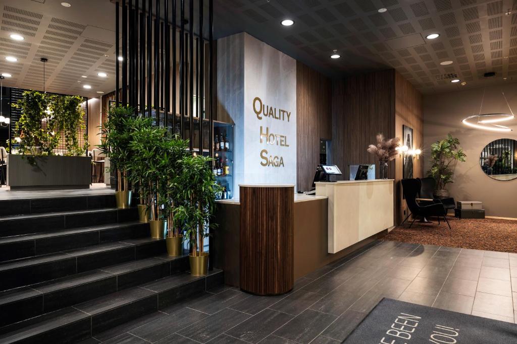 a lobby with stairs and a counter with plants at Quality Hotel Saga in Tromsø