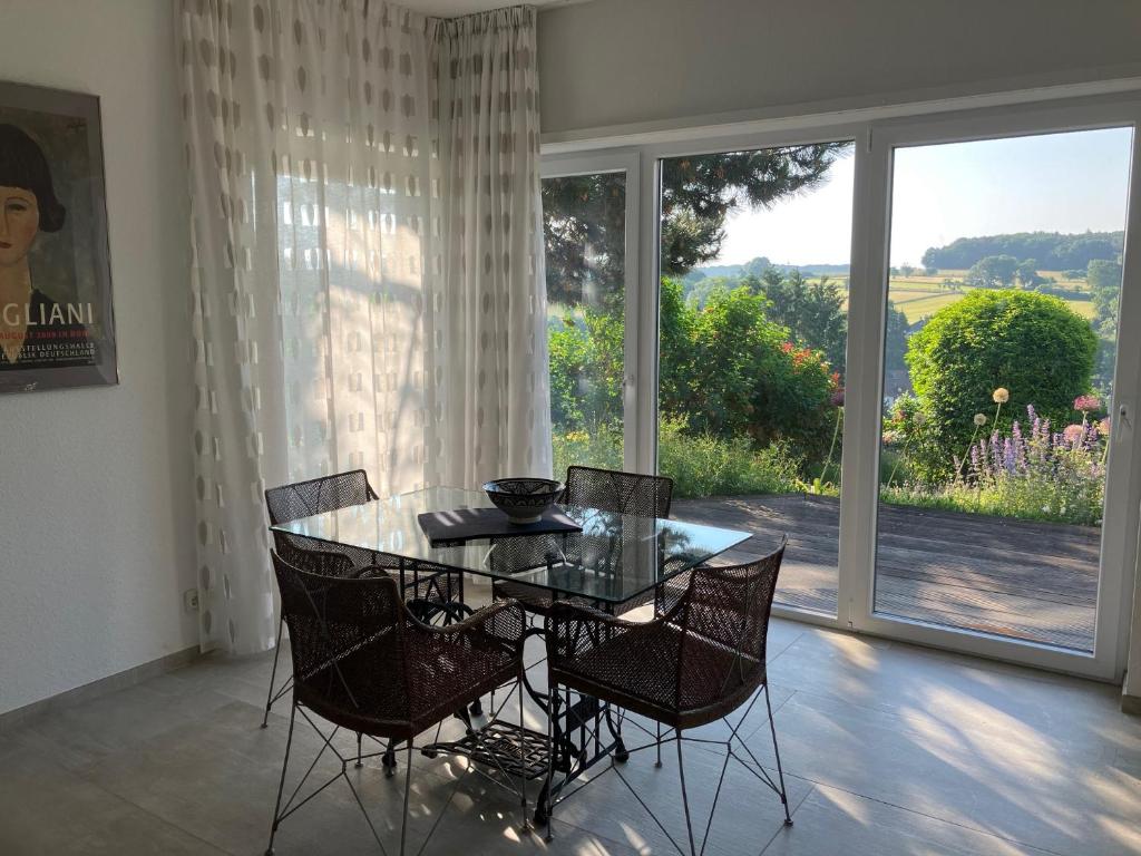 een eetkamer met een tafel en stoelen en een groot raam bij GARTENBLICK Ferienwohnung oder Mieten auf Zeit, nahe Bonn-Bad Godesberg in Wachtberg