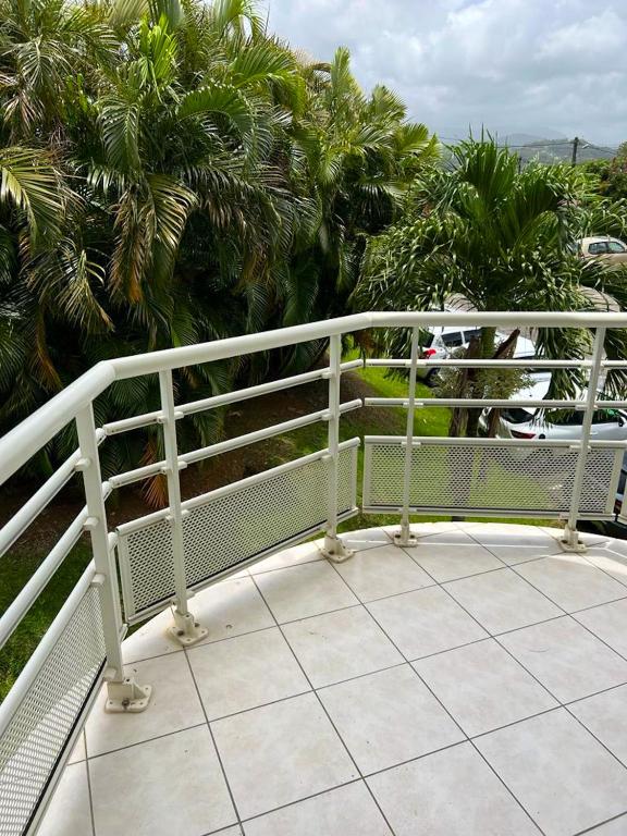 um corrimão branco numa varanda com palmeiras em Appartement d'une chambre avec balcon a Le Lamentin a 7 km de la plage em Le Lamentin