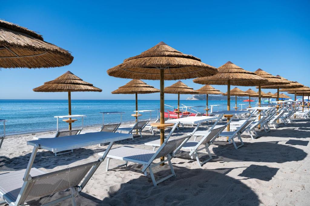 a row of chairs and tables with umbrellas on a beach at Palazzo Tirso MGallery Cagliari in Cagliari