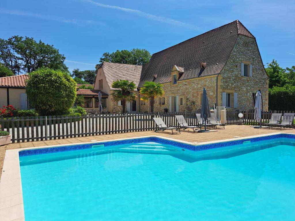 une grande piscine bleue en face d'une maison dans l'établissement La Barde Montfort, votre maison d'hôtes à 4 kms de Sarlat Dordogne, à Vitrac