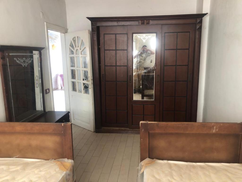 een kamer met 2 bedden en een houten deur bij المريوطية الرئيسي in ‘Ezbet Abu Bakr ‘Allâm