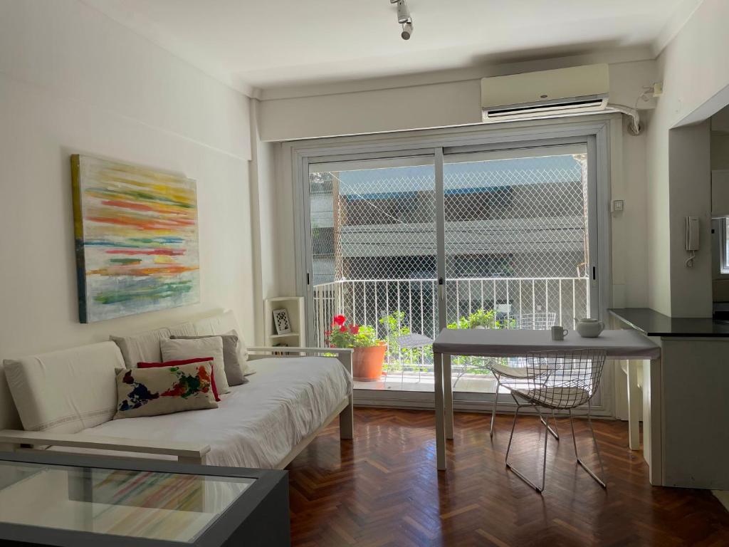 ein Wohnzimmer mit einem Sofa, einem Tisch und einem Fenster in der Unterkunft Studio Palermo Hermoso Con Balcon in Buenos Aires