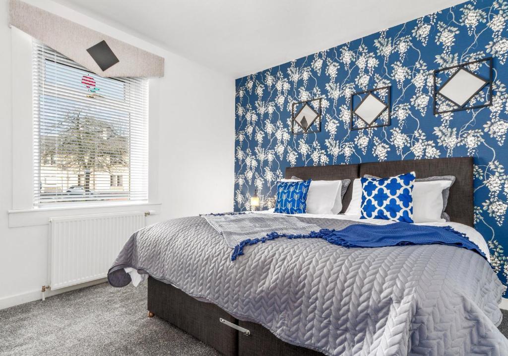 ein Schlafzimmer mit einem Bett mit blauen und weißen Tapeten in der Unterkunft Back'o'Barns Apartment by Klass Living Hamilton in Hamilton