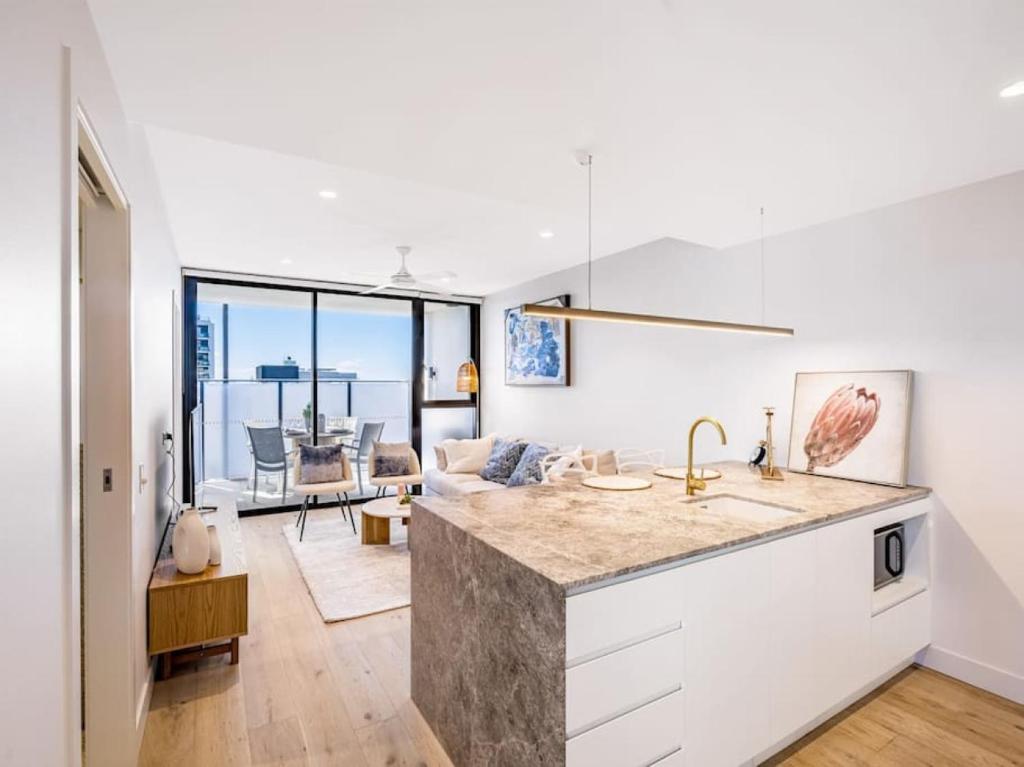 a kitchen with a counter and a living room at Conveniently located 2BR apt with rooftop pool at Milt in Brisbane