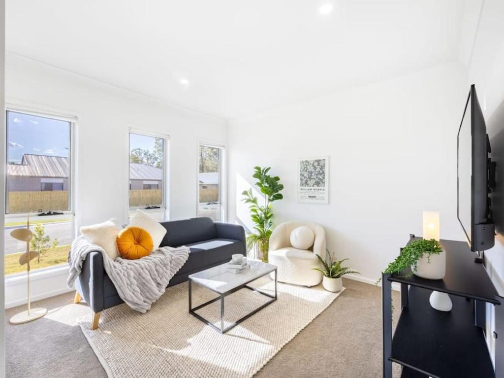 a living room with a blue couch and a table at Well-decorated 4BR Family home steps to mall in Browns Plains