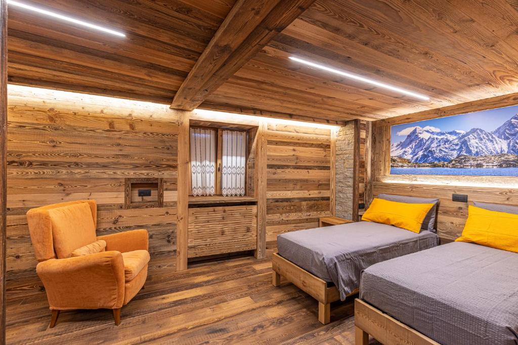卡斯波喬的住宿－ValmalencoAlpina，小木屋卧室配有两张床和椅子