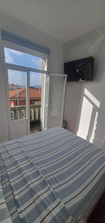 een slaapkamer met een bed en een groot raam bij Habitación pequeña con balcon in Vigo