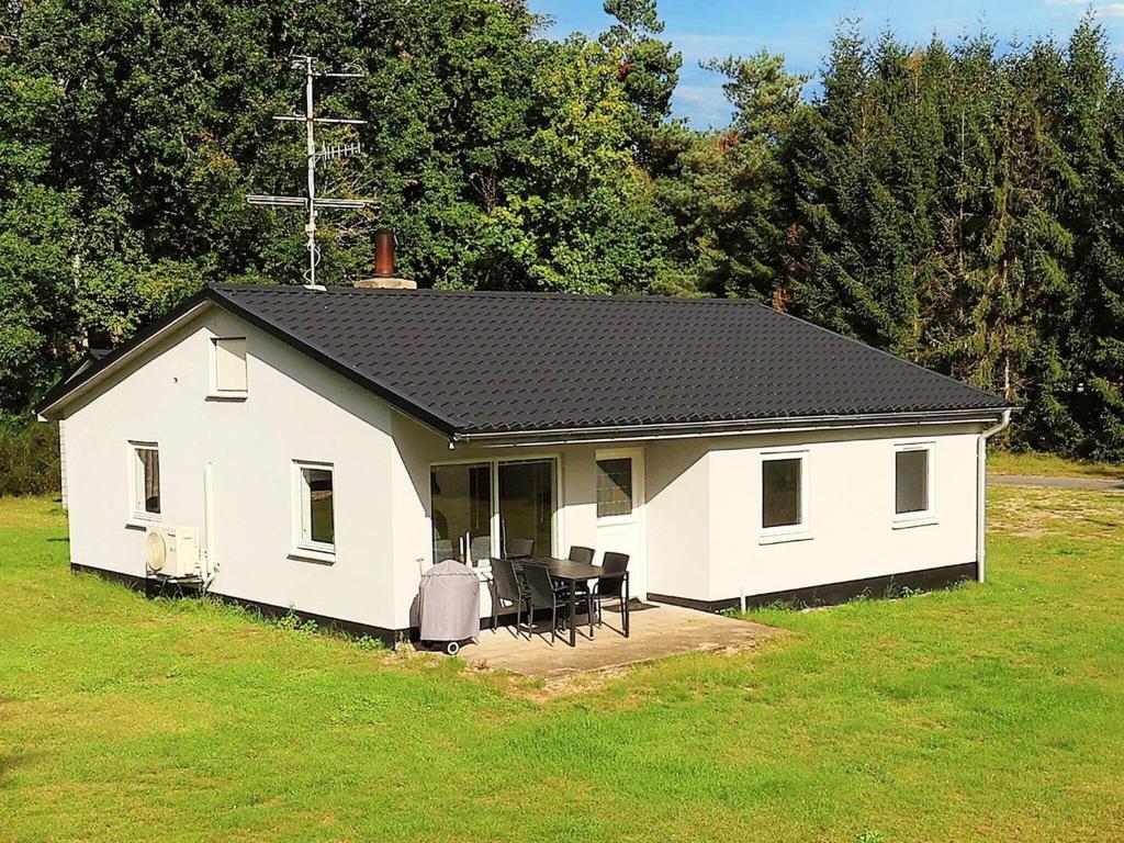 une petite maison blanche avec un toit noir dans l'établissement Holiday home Læsø, à Læsø