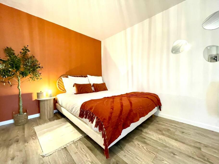 1 dormitorio con 1 cama con pared de color naranja en Grand Studio Chez Soi - Queen size bed - Terrasse, en Oyonnax