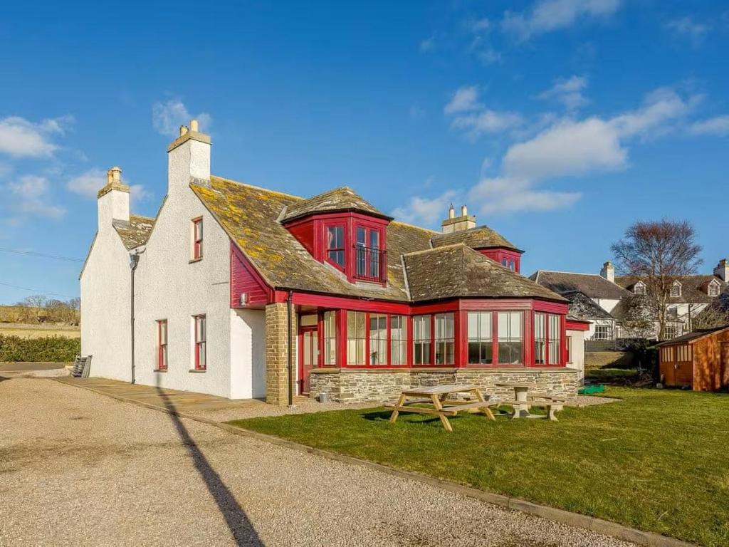 a red and white house with a picnic table in front of it at Craiglea Lodge in Latheron