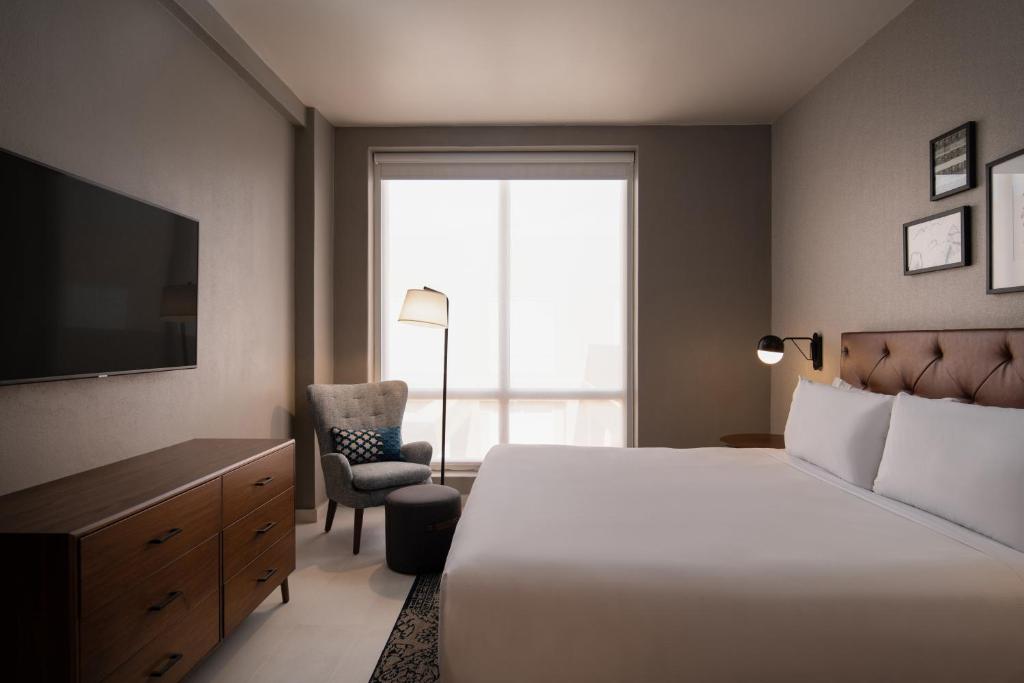 Un dormitorio con una cama, un televisor y una silla. en Four Points by Sheraton , en Punta Cana